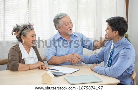 Smiling satisfied senior couple making sale purchase deal concluding contract from real estate agent,happy older family and broker shake hands agreeing to buy new house at meeting. Royalty-Free Stock Photo #1675874197