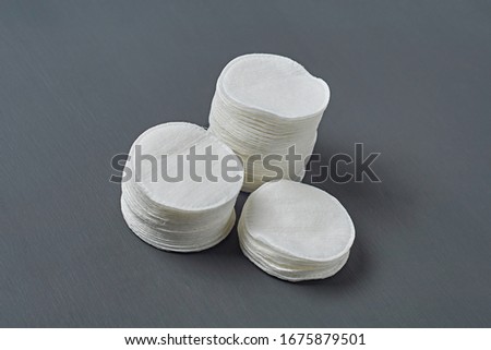 Heap of round cotton pads for hygiene lies on dark concrete table. Close-up