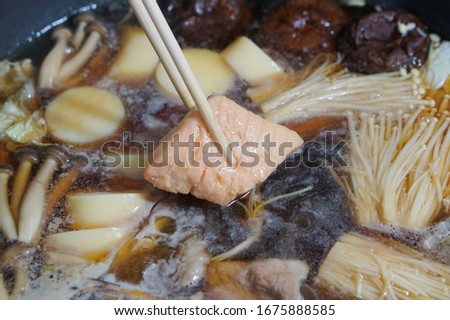 close up picture of boiled Japanese hot pot  with salmon which be grabbed with chopsticks
