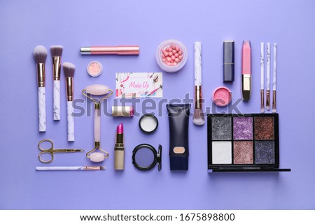 Decorative cosmetics and accessories with business card of makeup artist on color background