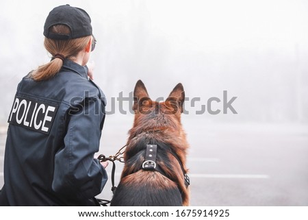 Female police officer with dog patrolling city street Royalty-Free Stock Photo #1675914925