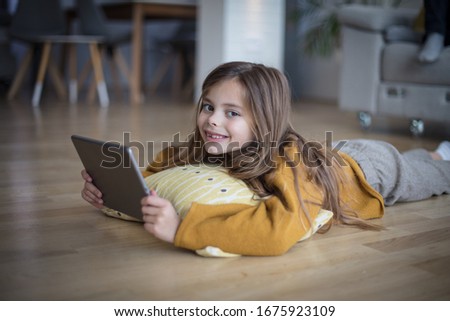 Sometimes is a great to stay home. Little girl lying on floor and using digital tablet.