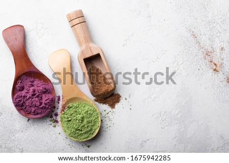 Top view of bamboo spoons with cinnamon powder, green matcha tea and acai berries powder Royalty-Free Stock Photo #1675942285