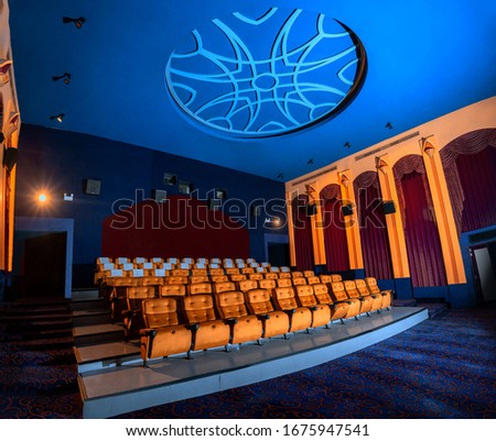 Large cinema theater interior with seat rows for audience to sit in movie theater premiere by cinematograph projector. The cinema theater is decorated in classical for luxury feel of movie watching. Royalty-Free Stock Photo #1675947541