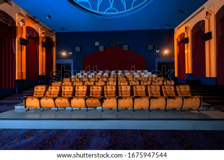 Large cinema theater interior with seat rows for audience to sit in movie theater premiere by cinematograph projector. The cinema theater is decorated in classical for luxury feel of movie watching. Royalty-Free Stock Photo #1675947544