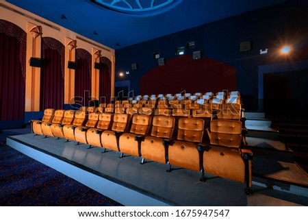 Large cinema theater interior with seat rows for audience to sit in movie theater premiere by cinematograph projector. The cinema theater is decorated in classical for luxury feel of movie watching. Royalty-Free Stock Photo #1675947547