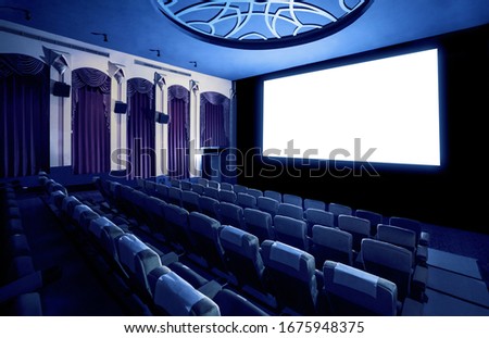 Cinema theater screen in front of seat rows in movie theater showing white screen projected from cinematograph. The cinema theater is decorated in classical style for luxury feeling of movie watching. Royalty-Free Stock Photo #1675948375