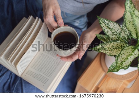 Woman holding a cup and reading a book. Royalty-Free Stock Photo #1675970230
