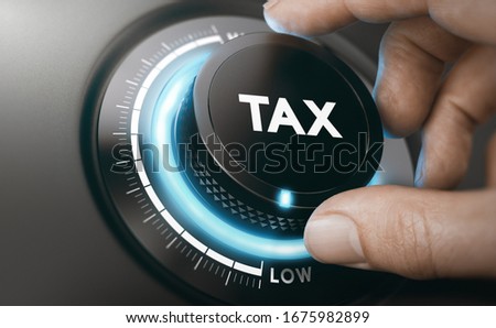Finger turning a tax knob with blue light to reduce taxes. Lowering taxable income concept. Composite image between a hand photography and a 3D background.