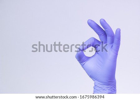 Ok sign is showed by left man hand in a purple medical glove on a white background. Okay