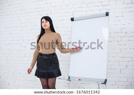 Girl businessman, teacher, trainer teaches and talks about a new project standing near the blackboard