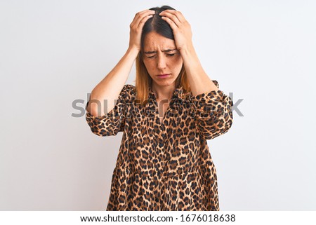 Beautiful redhead woman wearing elegant animal print shirt over isolated background suffering from headache desperate and stressed because pain and migraine. Hands on head.