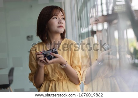 Asian woman photographer take a picture by film camera.