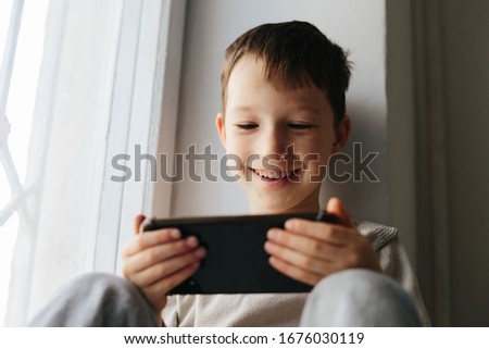 Little smiling child boy playing games or surfing internet on digital smartphone computer white isolated