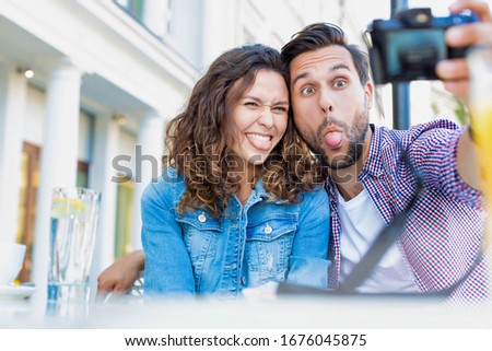Portrait of man making funny face while taking selfie with his beautiful girlfriend