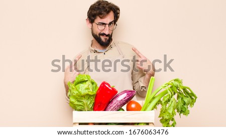green grocery man with a bad attitude looking proud and aggressive, pointing upwards or making fun sign with hands