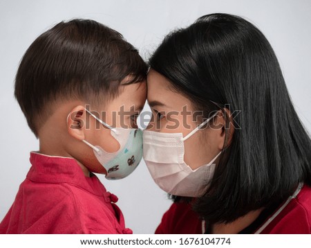 Portrait of asian family mom and son showing love and wearing protective mask trying to protect from virus epidemic over gray background. 
