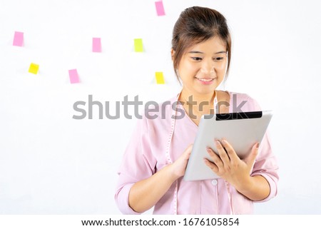 An Asian female designer is using a tablet. She is searching for new ideas to create her work.