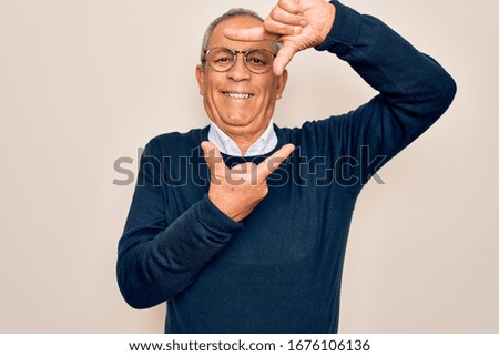 Senior handsome grey-haired man wearing sweater and glasses over isolated white background smiling making frame with hands and fingers with happy face. Creativity and photography concept.