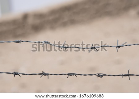 Barbed wire on fence with blurred background. Two line of barb wire, old steel fencing wire constructed with sharp points in horizontal