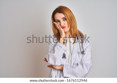 Redhead caucasian doctor woman wearing stethoscope over isolated background thinking looking tired and bored with depression problems with crossed arms.