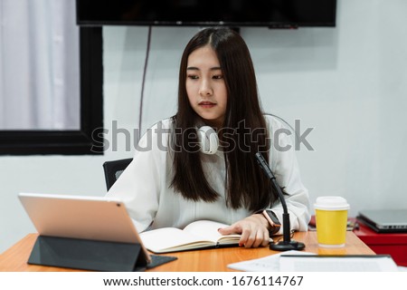 Black long hair girl in white shirt with white headphone around neck prepare herself for work by reading the information.