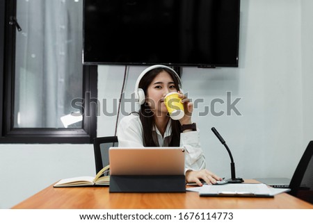 Black long hair girl in white shirt wearing white headphone drink hot coffee after turn off microphone and smile.