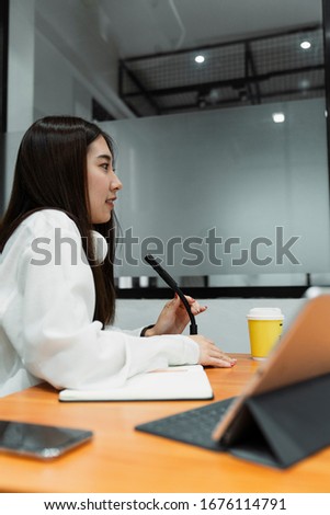 Black long hair girl in white shirt with white headphone around neck talk to colleague about the content for this podcast.