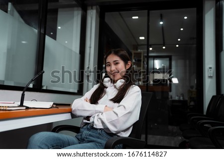 Black long hair podcaster girl in white shirt chilling sitting on the chair after broadcast.