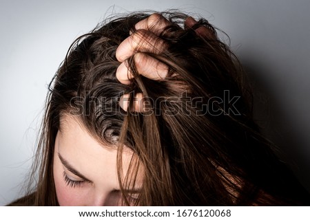 Young woman with dirty greasy hair on gray background.  Royalty-Free Stock Photo #1676120068