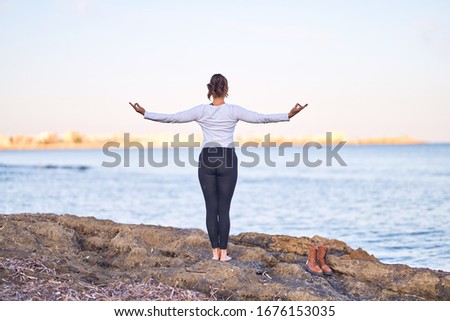 Young beautiful sportwoman practicing yoga. Coach teaching tree pose at the beach