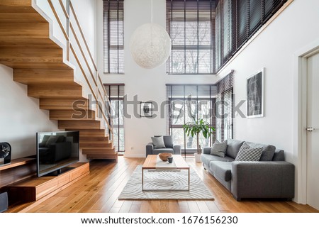 Two-floor apartment with spacious living room with wooden stairs, hardwood floor and many, big windows Royalty-Free Stock Photo #1676156230