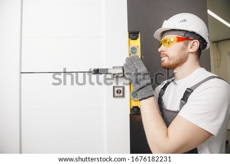 Carpenter worker installation process of wood door hinge tool level. Royalty-Free Stock Photo #1676182231