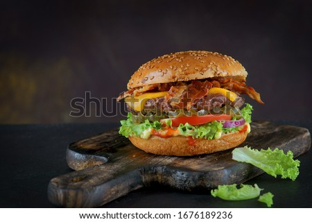 Burger with bacon and cheese on a dark background