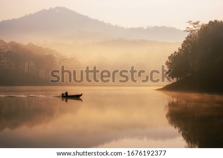 Sunset at Tuyen lam lake, Dalat, Vietnam. When sunset, an old fishman comes back home on the fuzzy mist