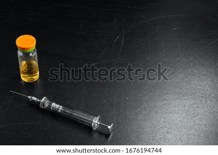 Glass syringe and a bottle with a vaccine on a black background close-up
