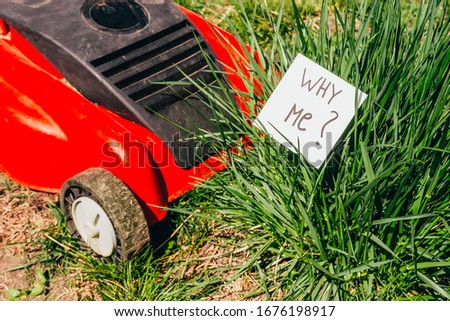 close up view of electric lawn mower cutting a bush with a sign wht me ? . time to mow concept