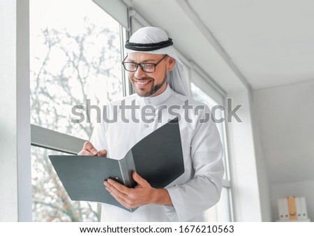 Handsome Arab businessman near window in office