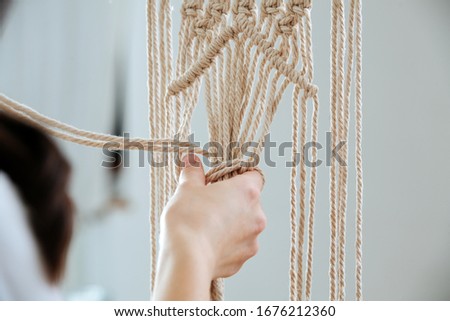 The middle knots of macrame, the view from behind the shoulder close-up of the girl's hand, she ties knots