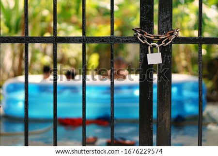 Concept picture : Padlock with chain on gate. Blurred background of children playing in the home area.