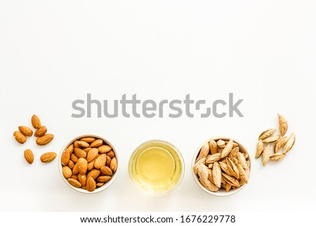 Almond oil - for cooking - in glass bowl near nuts on white background top-down copy space