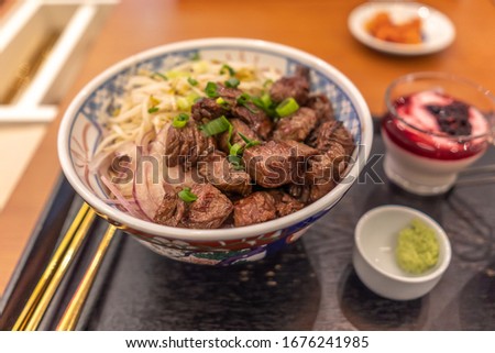 Meal with onions, host herbs and steak pieces on rice