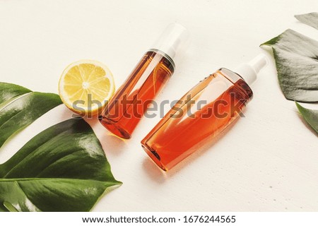 Summer sunscreen. Set of cosmetic bottles on a light background with green leaves. Place for text. Copyspase.