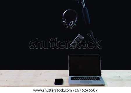 Laptop , headphones, phone and camera accessory on black background. Portable laptop with headset and mini stereo microphone on colored wooden background. Modern devices , Voice recording concept.