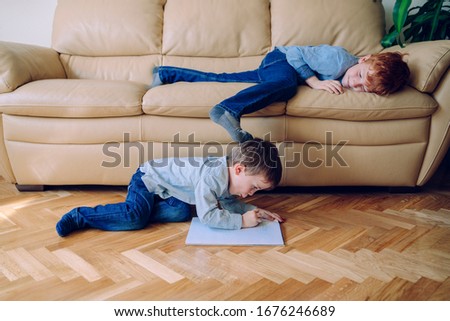 Bored siblings at home playing with each other on the house isolation. Quarantine for families in the house with children. Family indoors lifestyle. Kids doing homework grounded with no school. Royalty-Free Stock Photo #1676246689