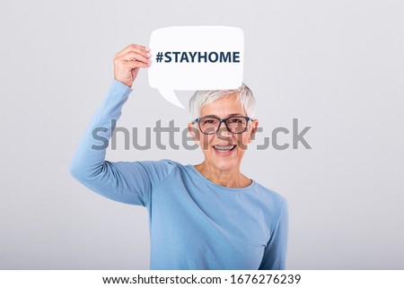 Mature woman holding Stay home phrase #stayhome on speech bubble isolated on background. Royalty-Free Stock Photo #1676276239