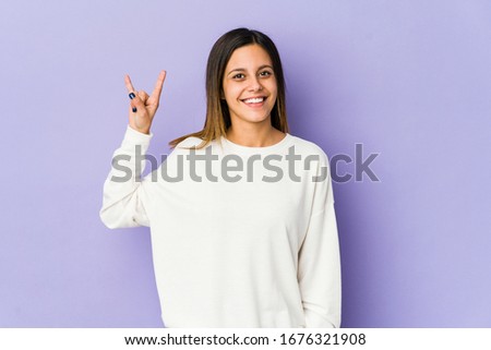 Young woman isolated on purple background showing a horns gesture as a revolution concept.