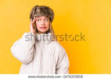 Young caucasian woman wearing a winter clothes isolated shouts loud, keeps eyes opened and hands tense.