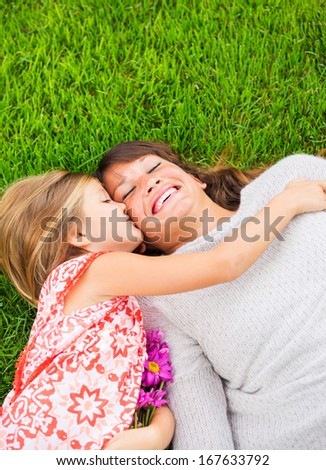 Happy mother and daughter relaxing outside on green grass. Spending quality time together, Real emotions