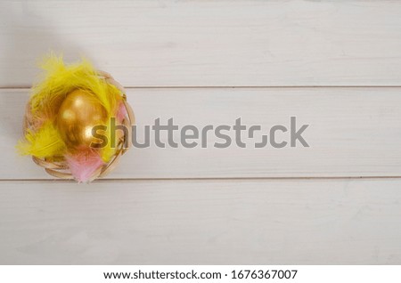 Easter card background. Easter golden egg on a white background in a feather nest with copy space. Happy easter. Flat lay.